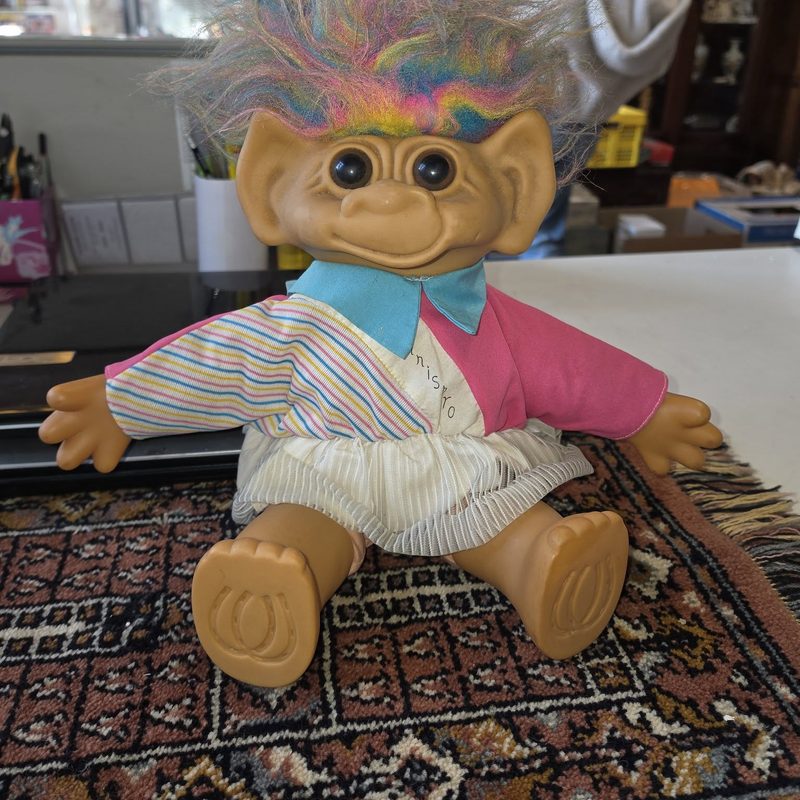 Trollpop met regenbooghaar op een tapijt in de kringloopwinkel in Deurne