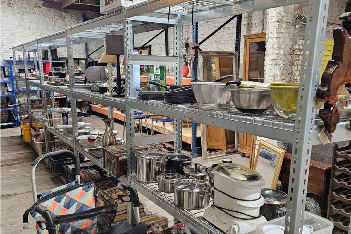 Spullen doneren aan de kringloop: rekken met tweedehands huisraad in de winkel in Deurne